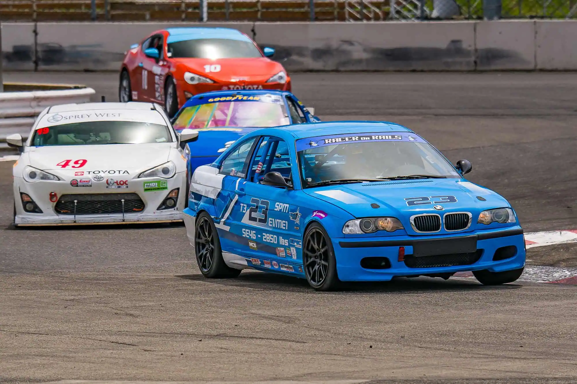 Chris Johnson driving the blue Racer on Rails BMW Spec E46 Touring 3 race car ahead of race traffic at Portland International Raceway.