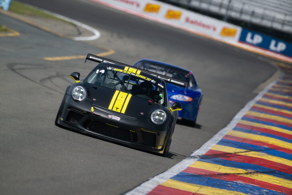 Ann Doherty drives the black-and-yellow Racer on Rails Porsche race car through a corner at Watkins Glen International.