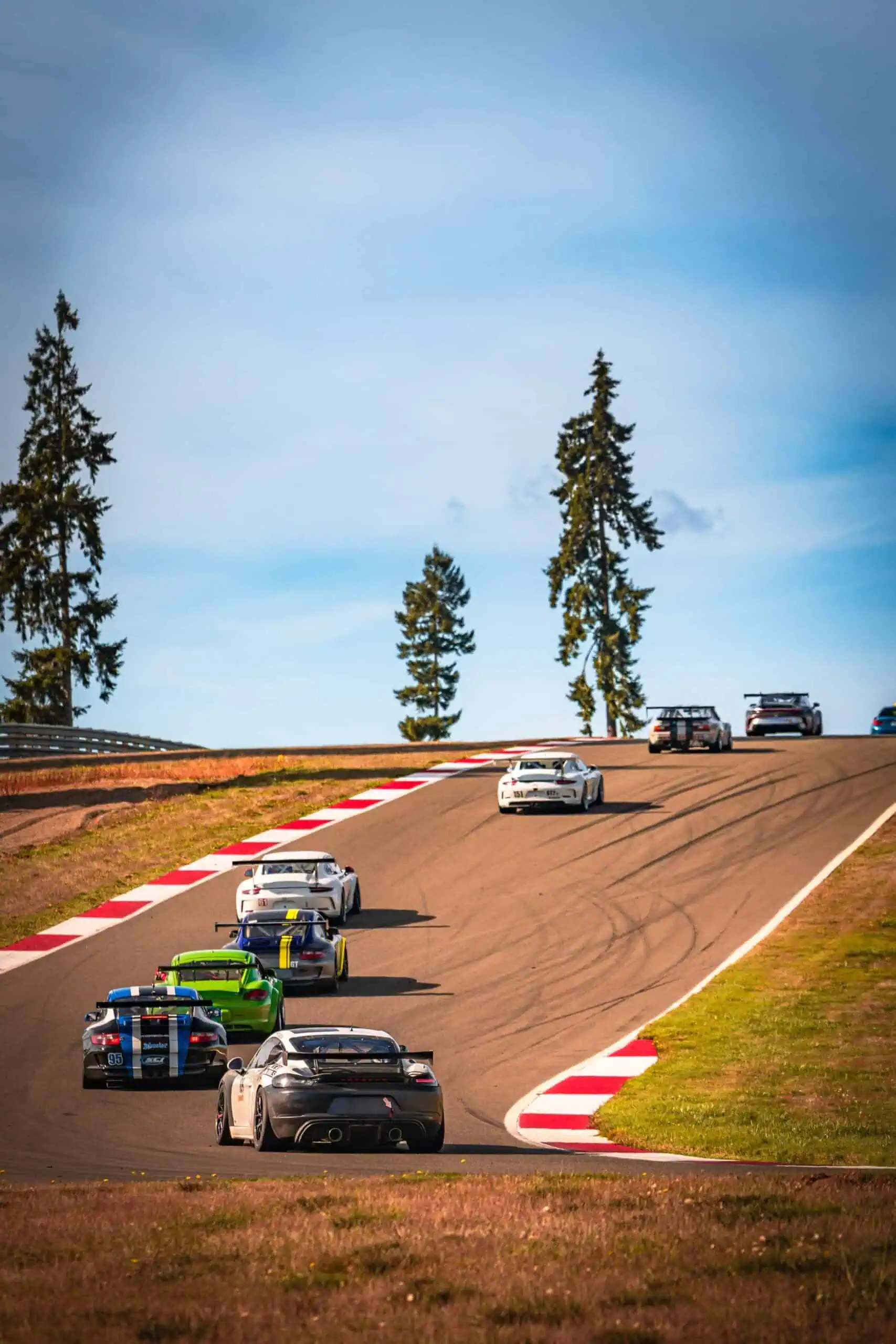 Porsche 718 Cayman GT4 Clubsport MR on track at the Ridge leading a pack of cars uphill