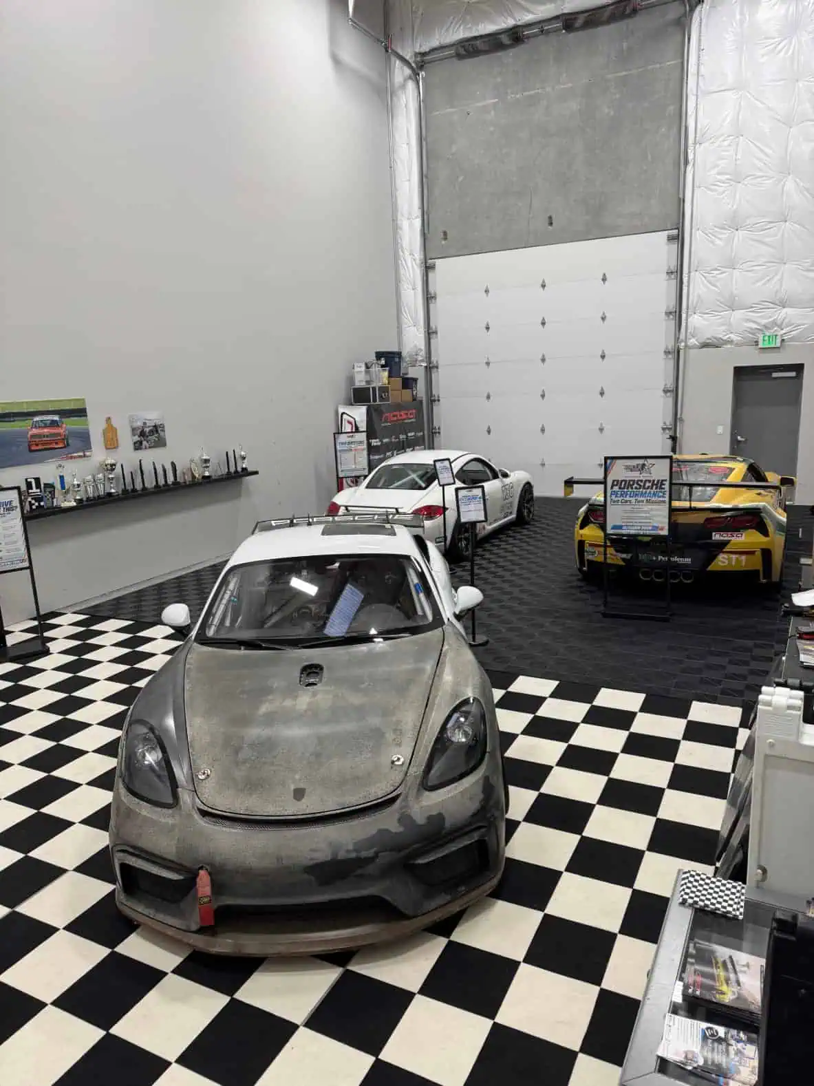 Porsche Cayman GT4 Clubsport MR and Dirk's #136 T3 Cayman side by side in the Racer on Rails showroom
