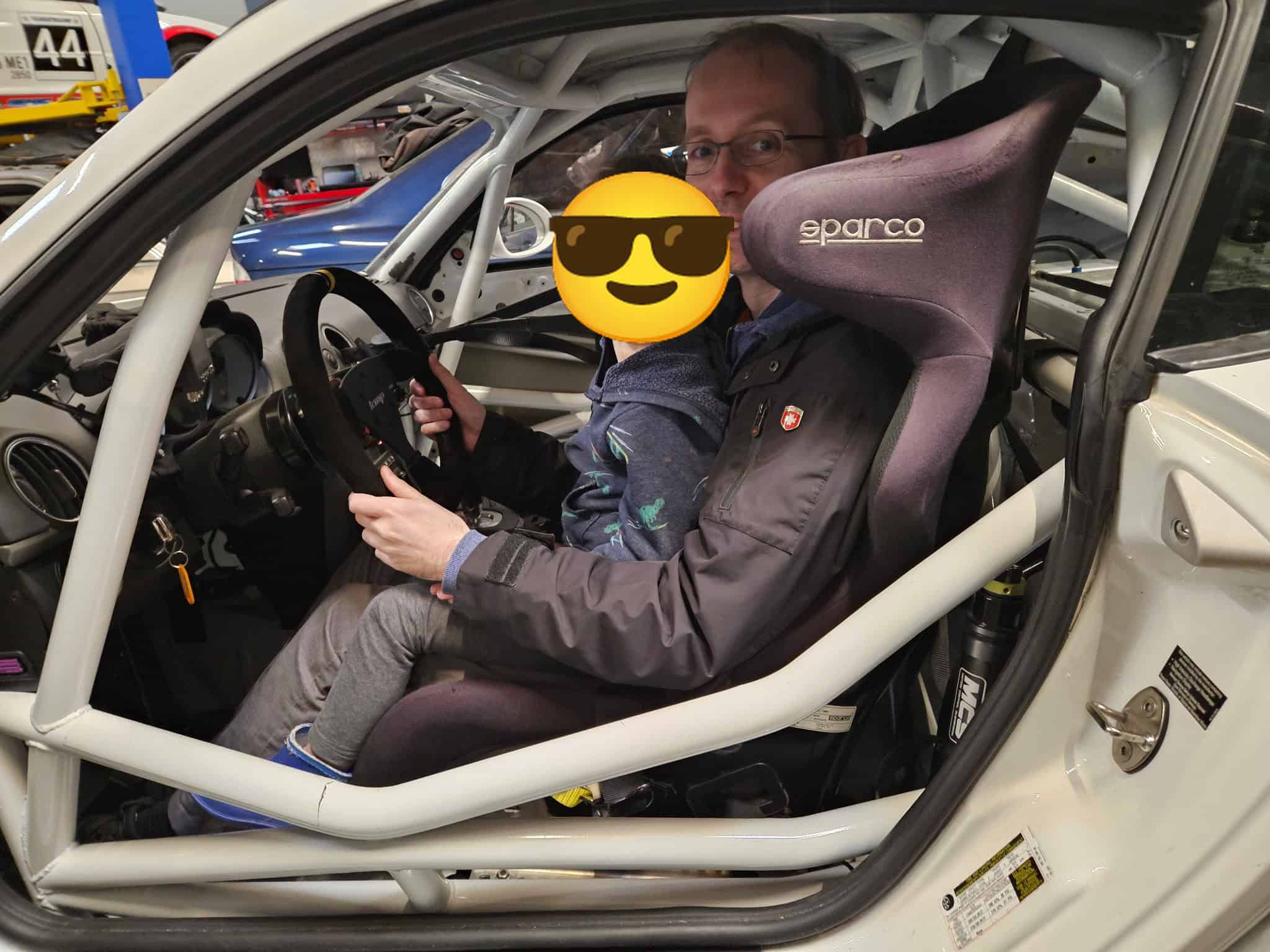A young visitor in the driver seat of the T3 Cayman, face covered by a sunglasses emoji for privacy